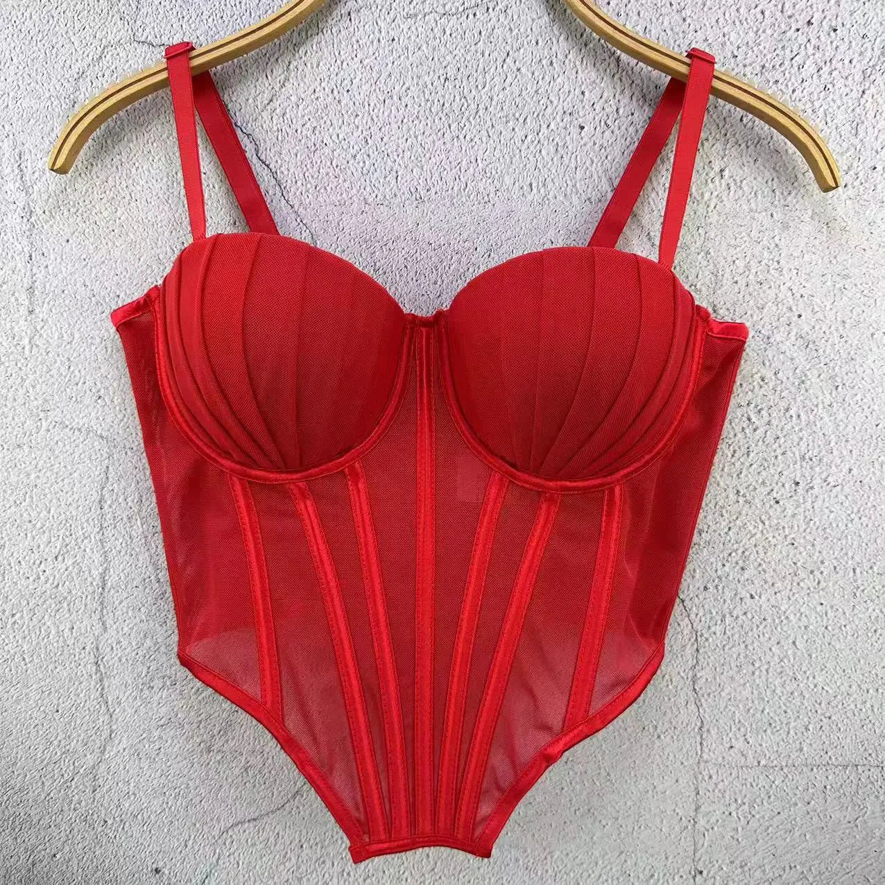 Red sexy clubwear bustier shirt with structured cups and sheer panels hanging on wooden hanger