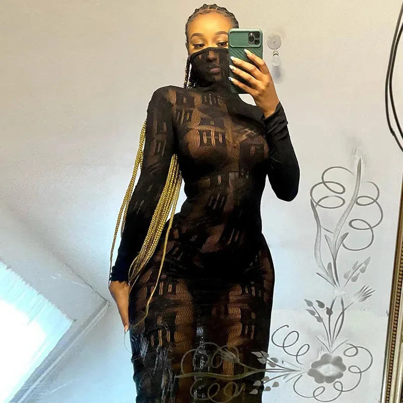 Woman wearing a black sheer long sleeve club dress taking a mirror selfie with phone