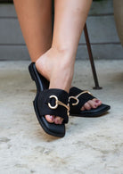 Maker's Shoes black wide fit vacation sandals with gold buckle detail on women's feet