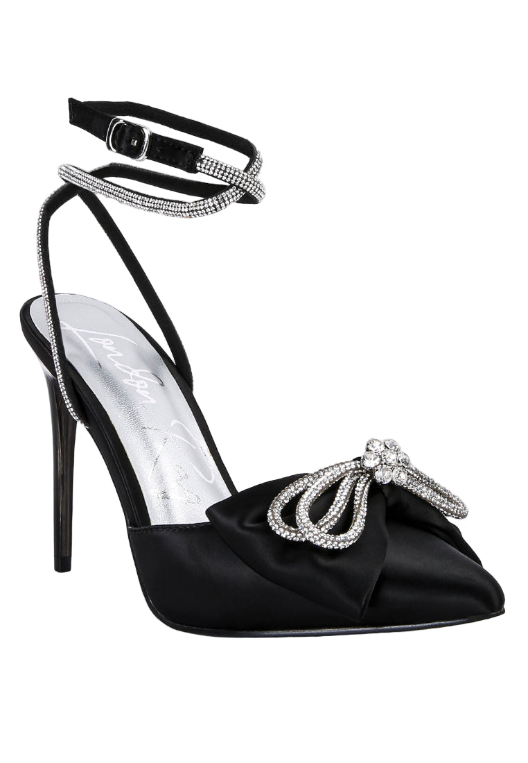 Black high-heeled shoe with decorative bow and ankle strap on a white background