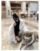 Cozy vacation scene featuring a model in a warm winter coat for women with a dog in a stylish lodge