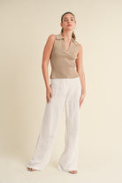 Aemi + Co women's henley tank top in tan paired with white wide-leg pants for a stylish look