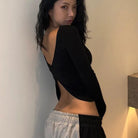 Woman wearing a stylish black backless crop top for women paired with casual sweatpants