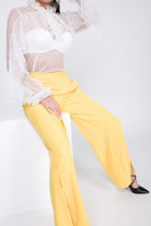 Women's yellow side slit trousers vacation style paired with a white sheer ruffled blouse