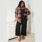 Plus-size model wearing a plaid casual vacation shirt styled with black wide-leg pants