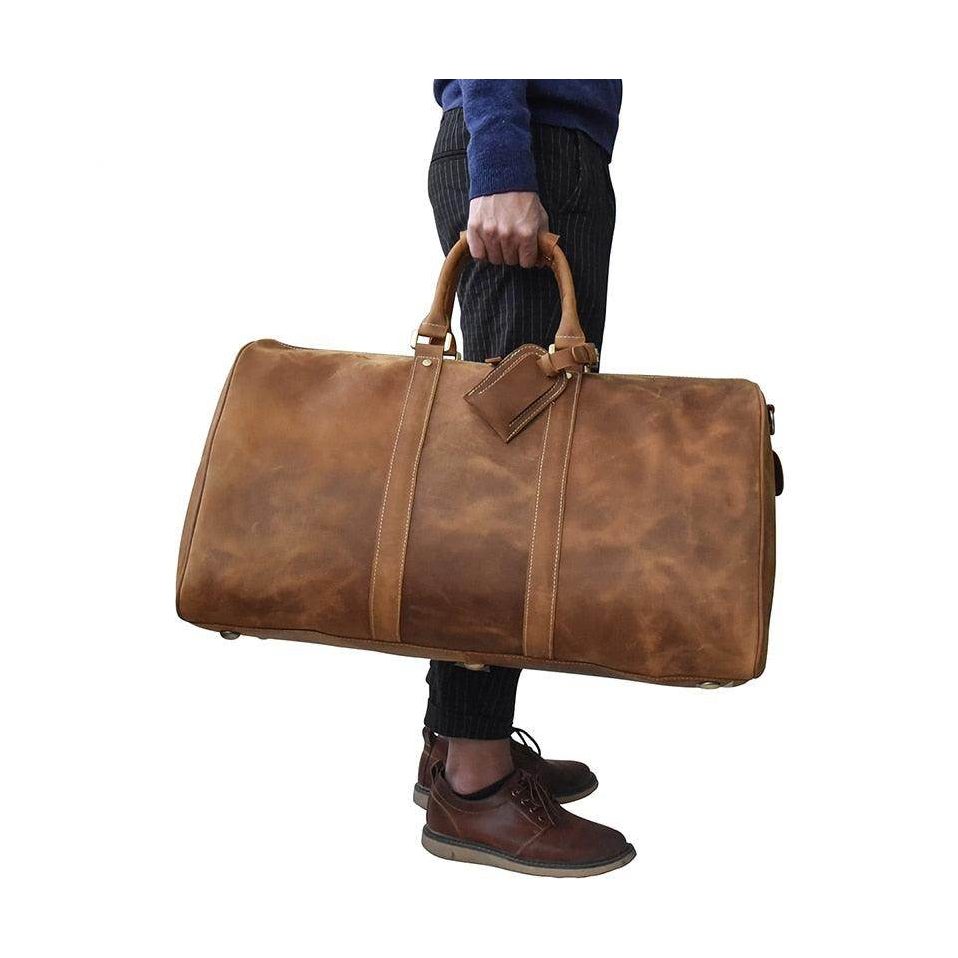 Large leather weekend bag in rustic brown held by a person, perfect for travel and stylish getaways