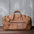 Stylish leather travel duffel bag in tan with multiple pockets and sturdy handles