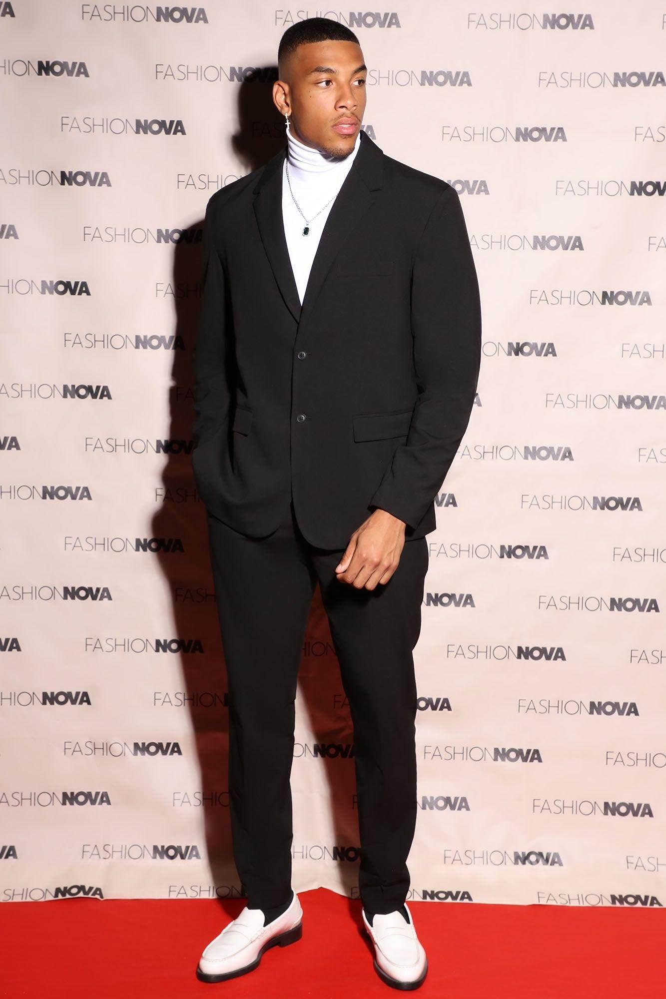 Fashion Nova modern suit jacket for men in black worn with a white turtleneck and stylish shoes