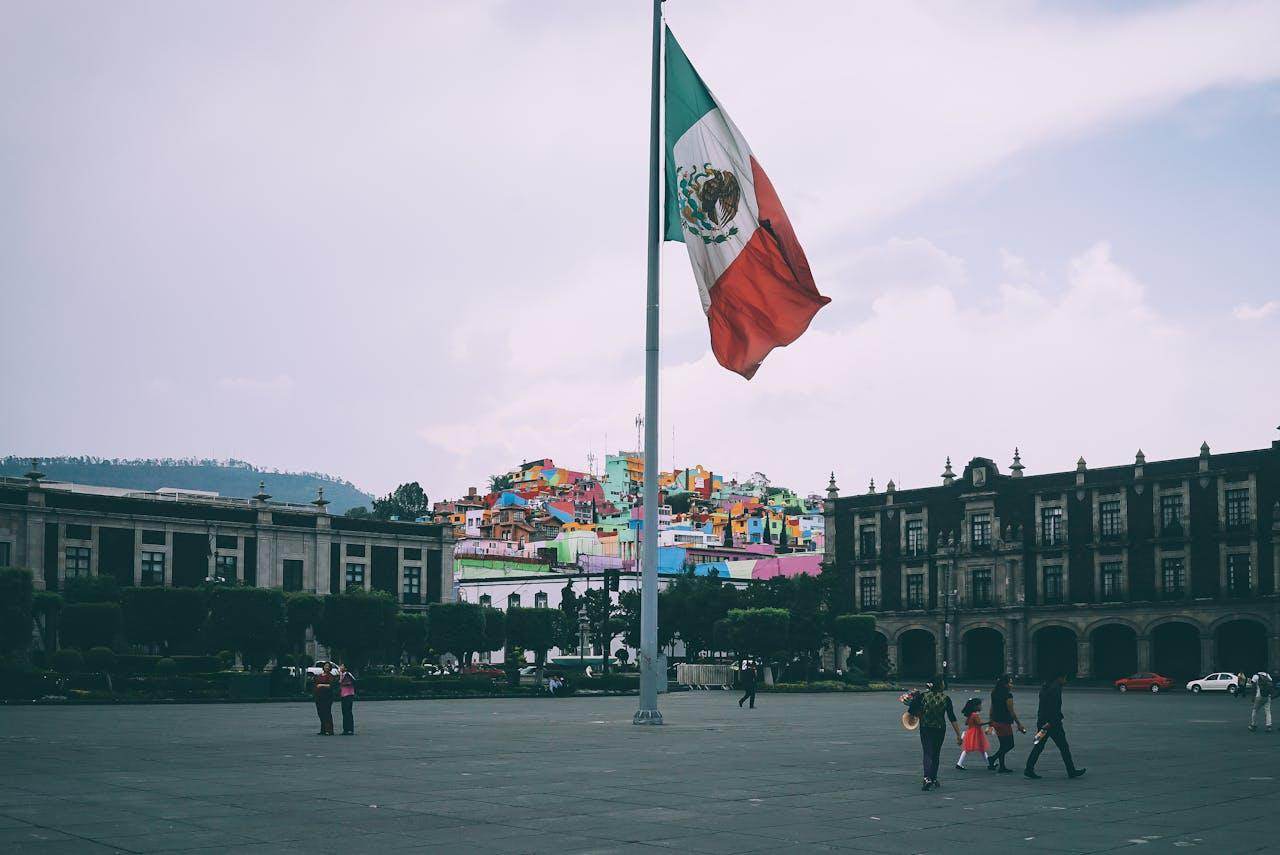 Cultural experiences in Mexico City showcasing the vibrant flag and historic architecture in the background