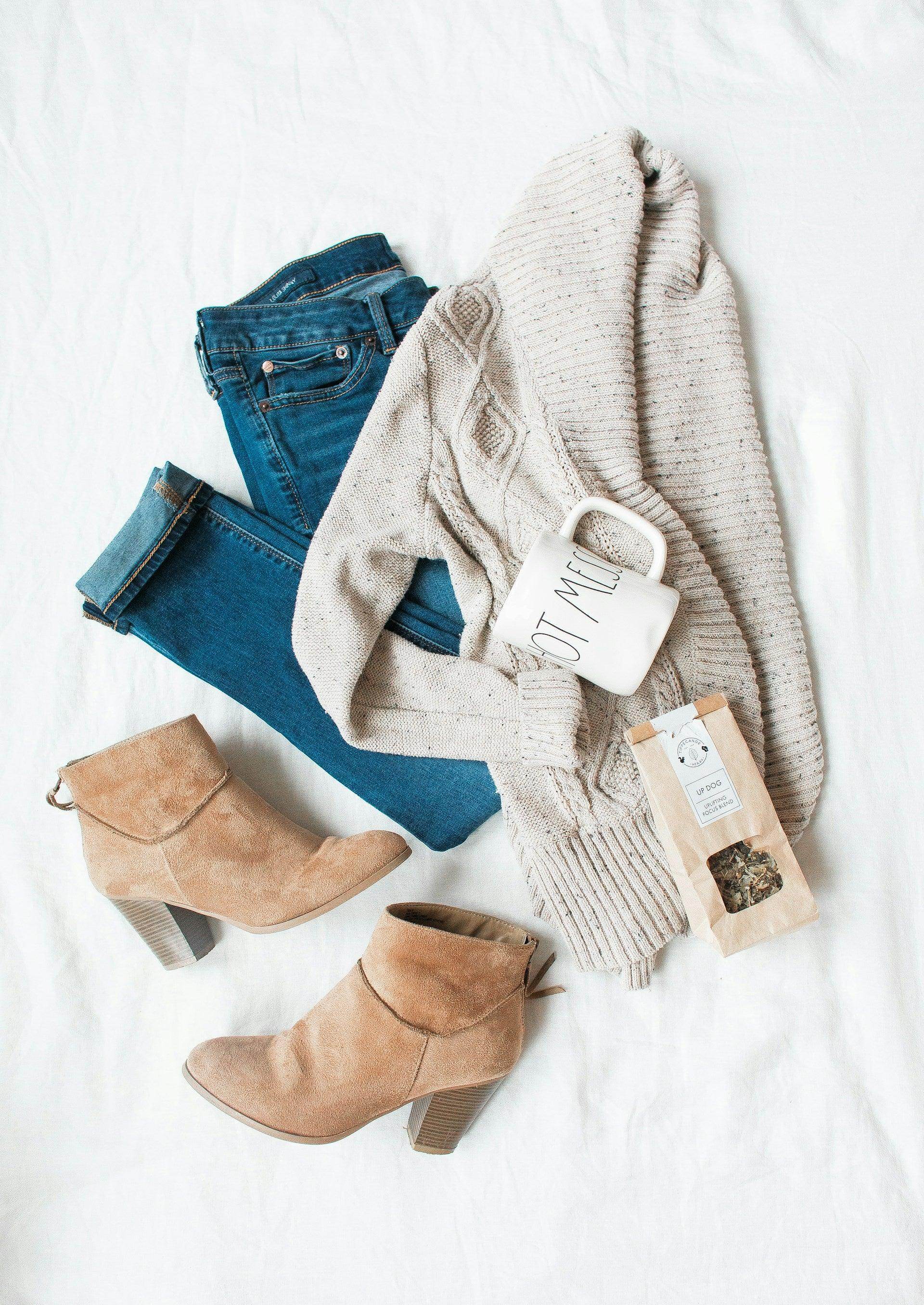 Versatile travel clothing featuring a cozy sweater, jeans, and stylish boots for vacation outfits
