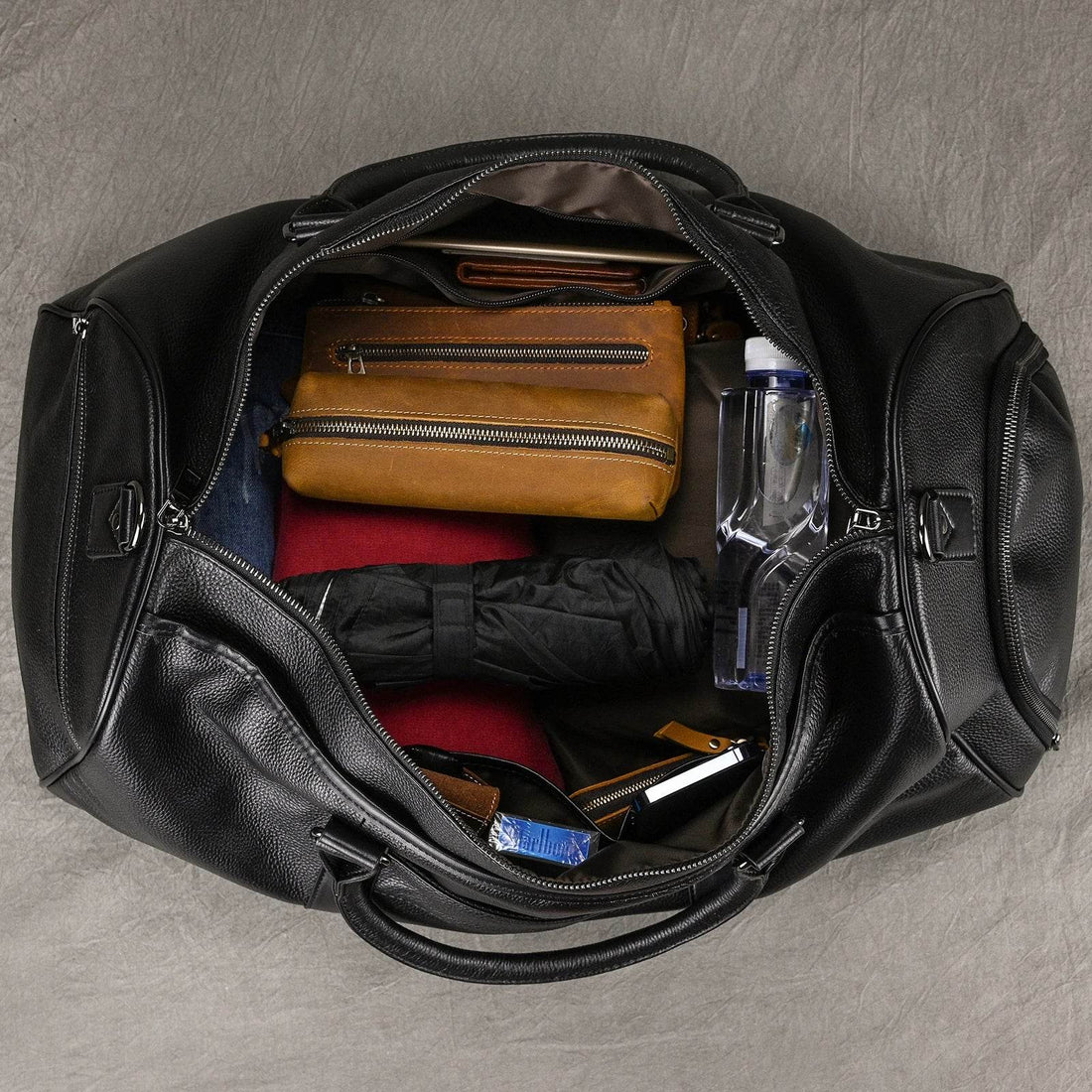 open black leather duffel bag with travel essentials inside