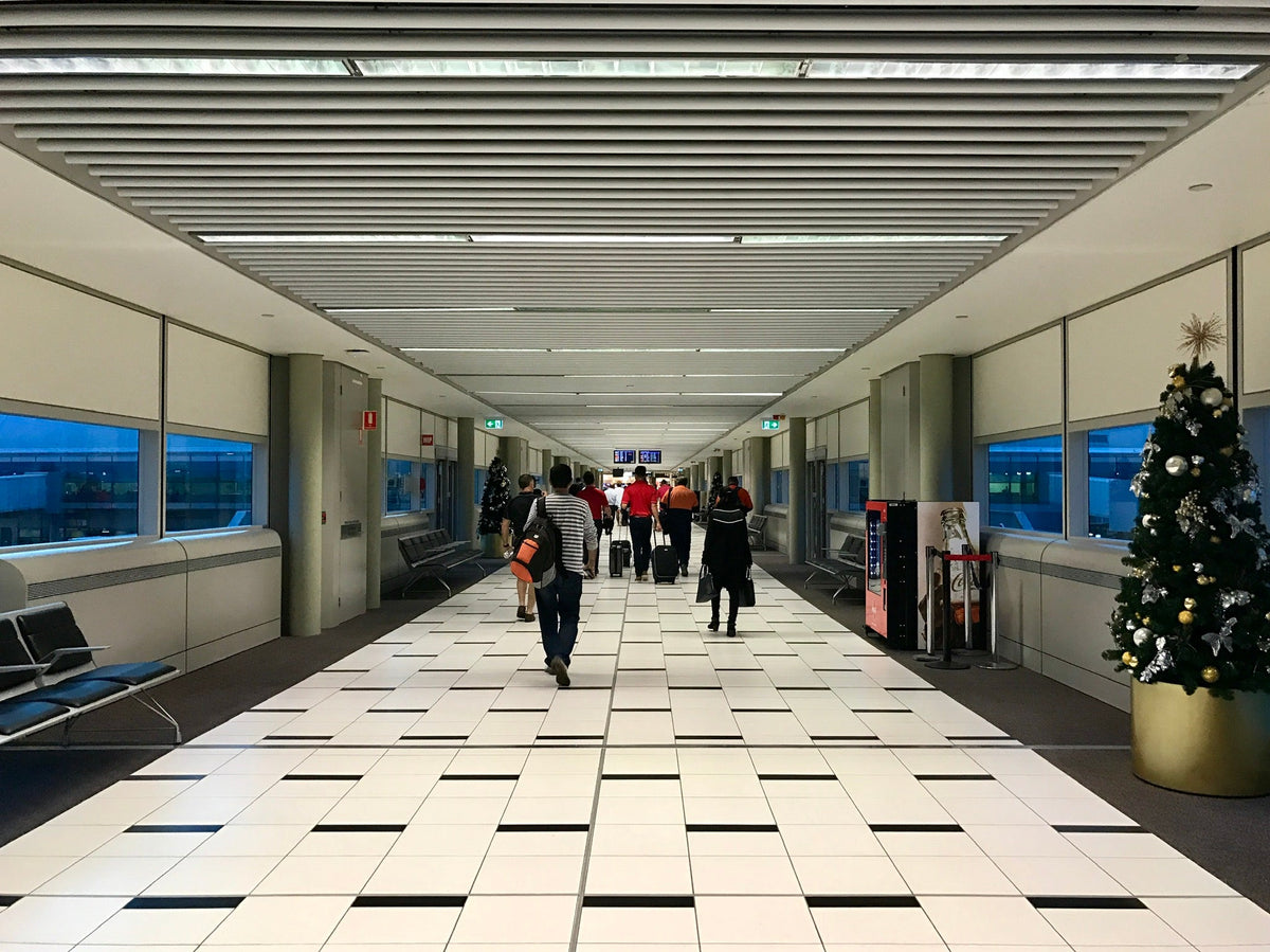 Travelers with luggage walking past a Christmas tree in an airport terminal