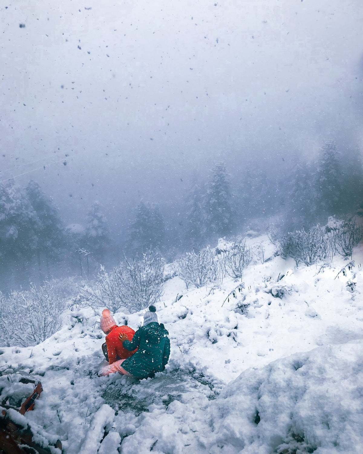 People bundled in winter coats sitting in heavy snowfall on a mountainside