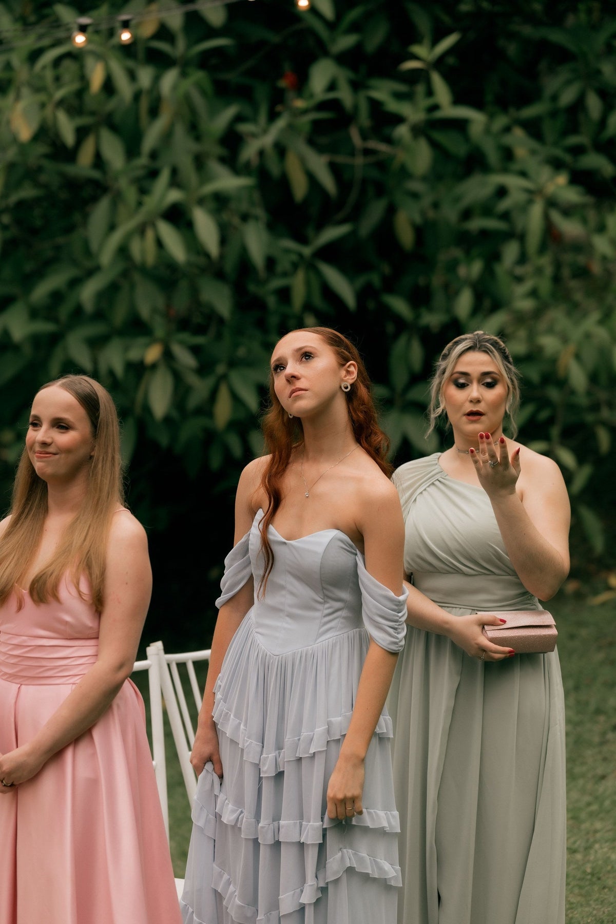 Women in elegant pastel formal dresses at an outdoor destination wedding