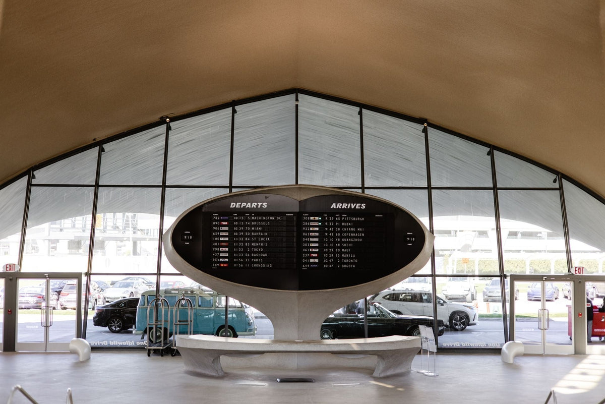 Vintage airport departures and arrivals board at the TWA Hotel at JFK, with evening light outside.