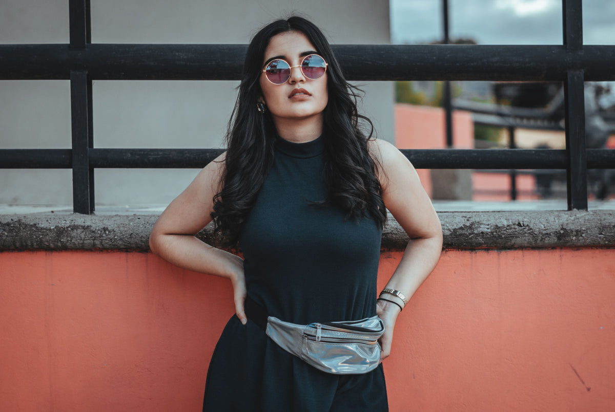 Woman in a black dress wearing a silver metallic fanny pack outdoors