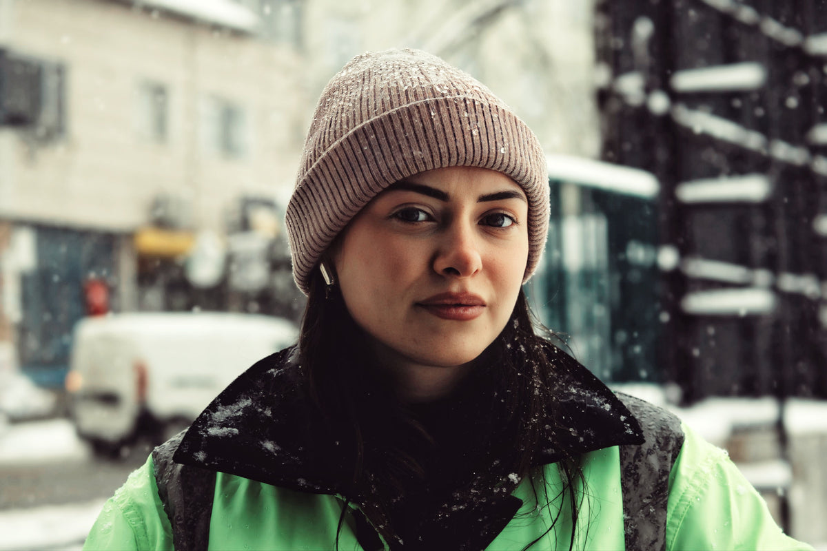A woman wearing a beanie outdoors in a winter cityscape