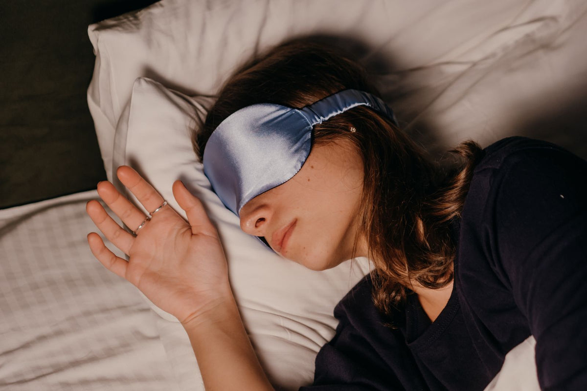 Woman sleeping while wearing a silk eye mask in bed