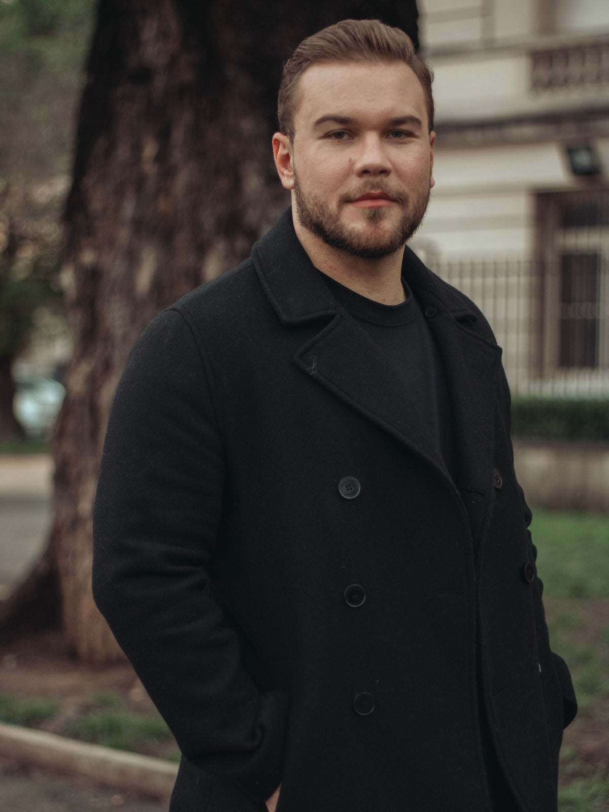 Man wearing a black wool-blend pea coat on a city street