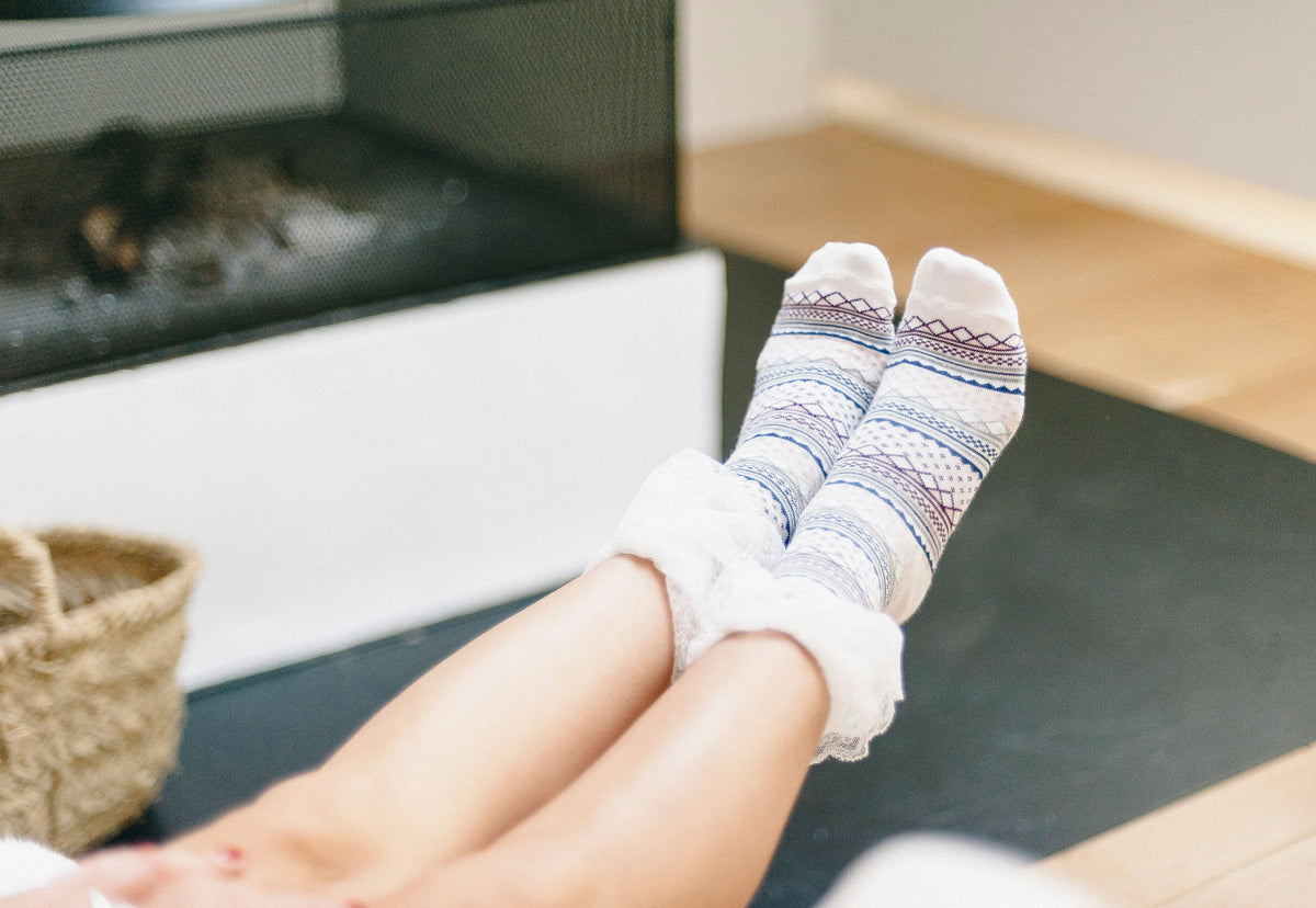 Feet in cozy wool socks propped up near a fireplace