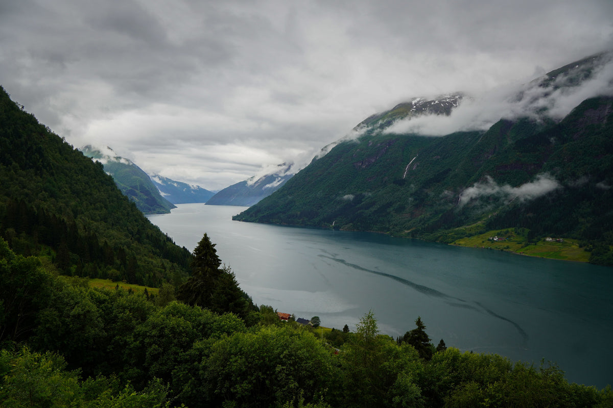 Scenic view of a Norwegian fjord with green mountains and low clouds