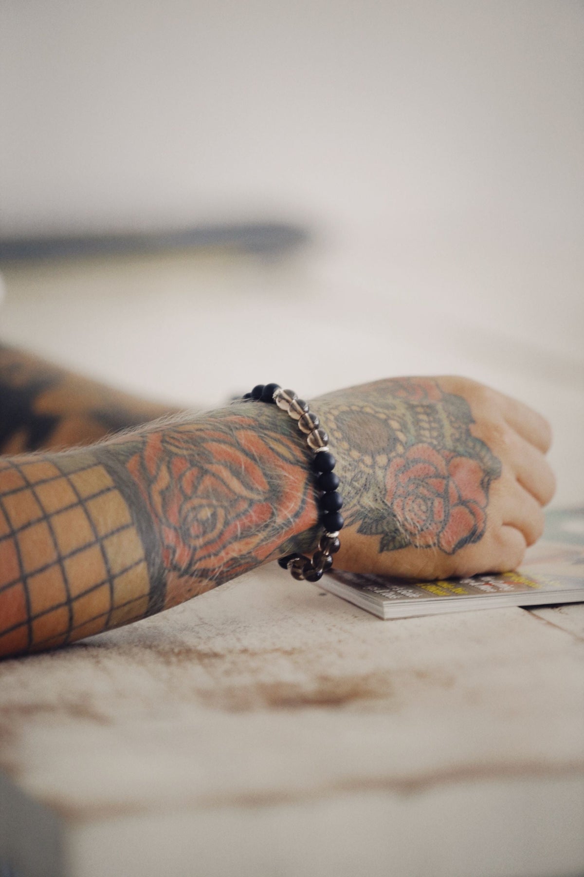 Tattooed hand wearing a beaded wristband bracelet