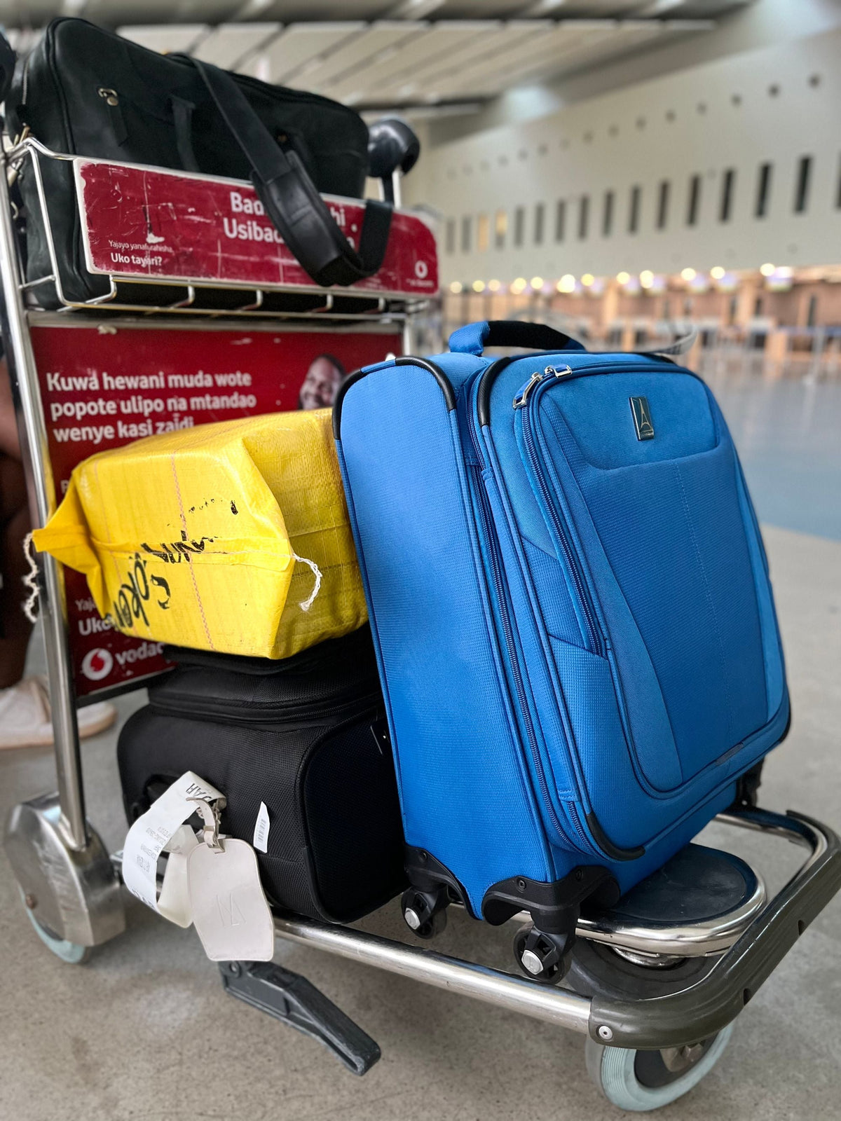 Colorful suitcases stacked on an airport luggage cart