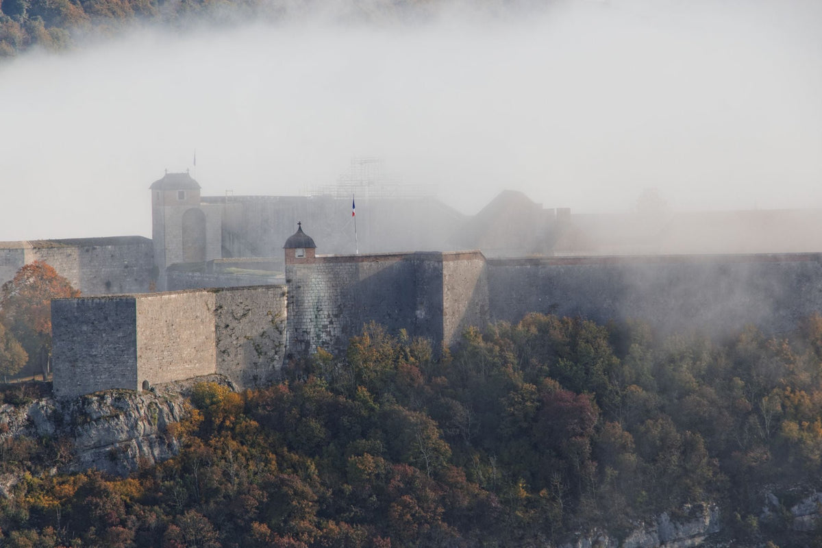 Old stone castle wrapped in fog on a hilltop