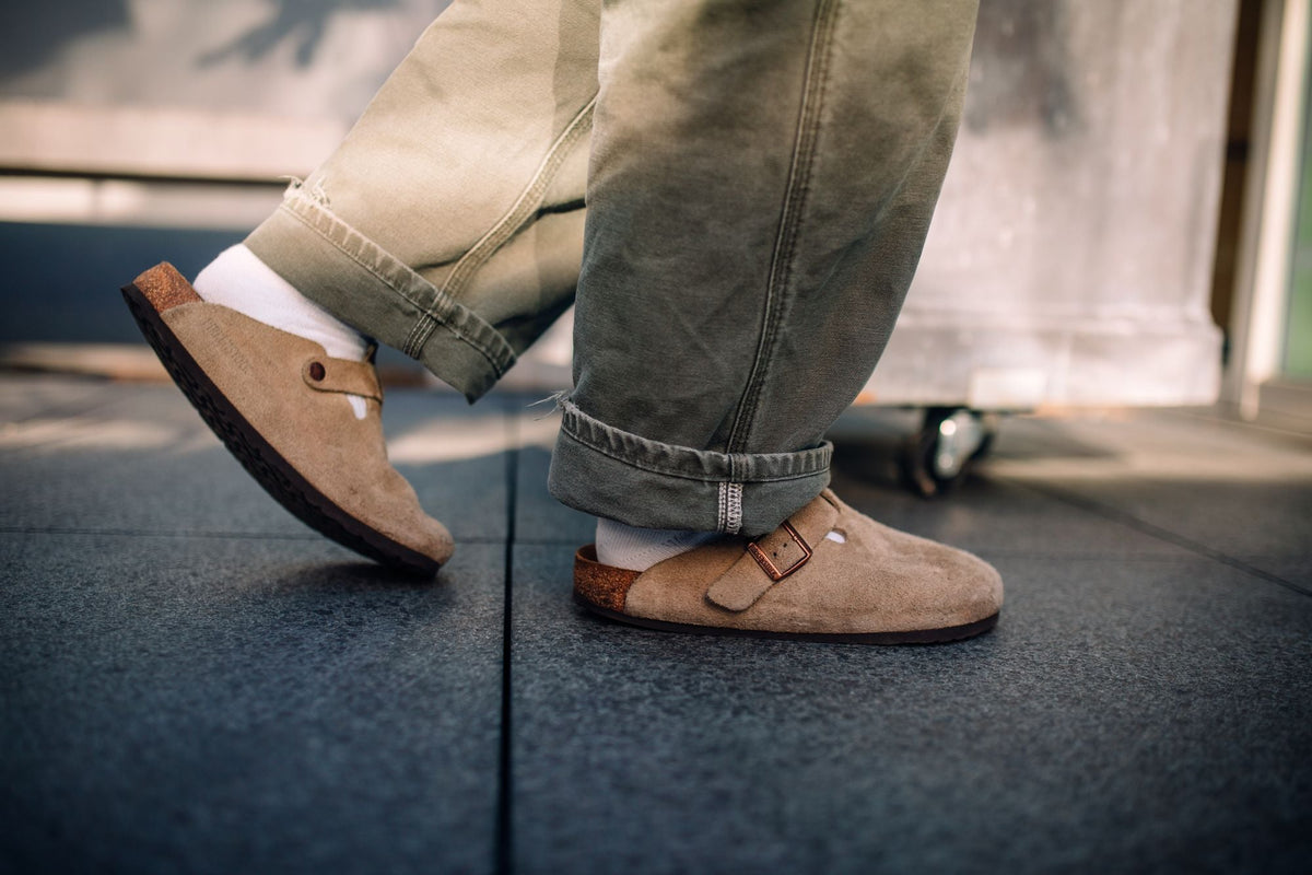 Close up of suede clog sandals worn with cropped pants