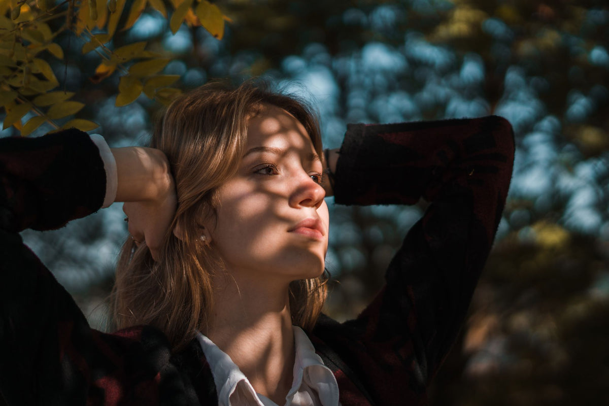 Woman wearing a plaid cardigan in dappled sunlight
