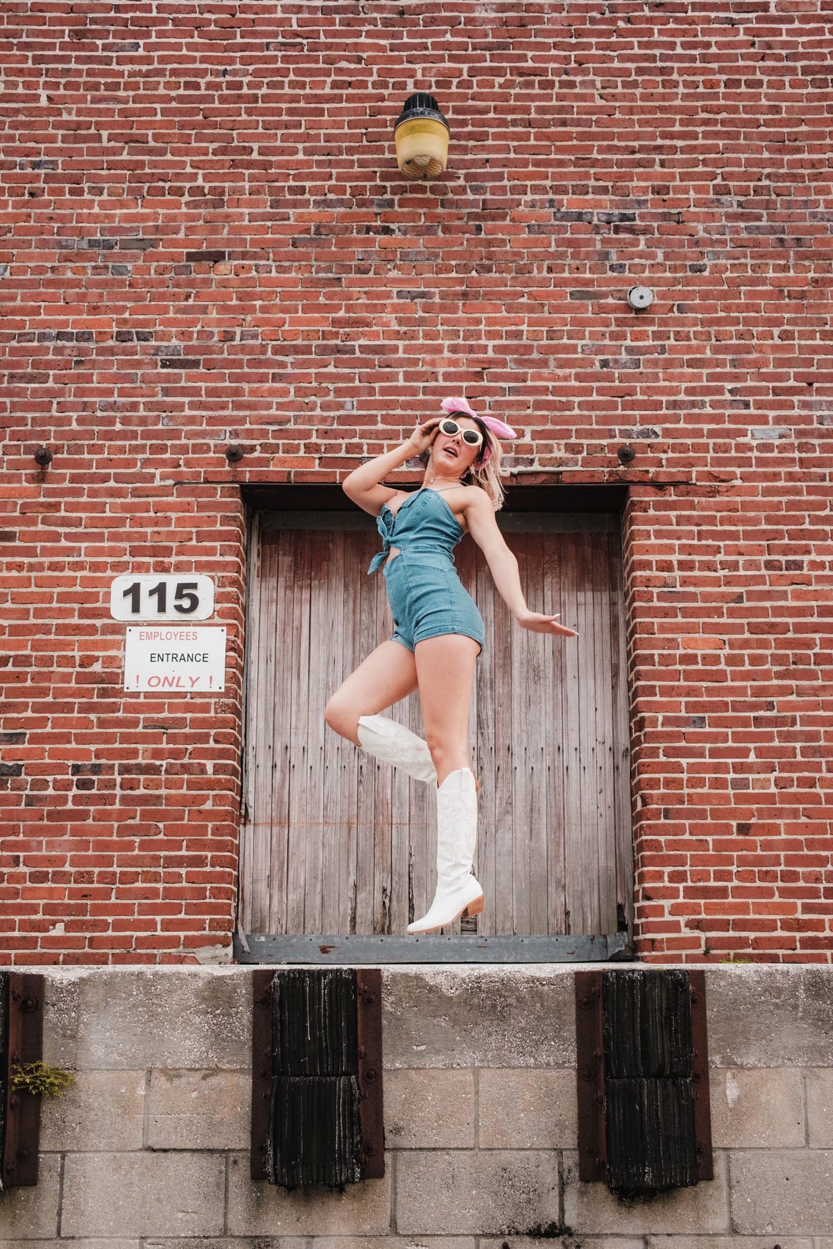 Woman wearing a denim romper jumpsuit and white boots