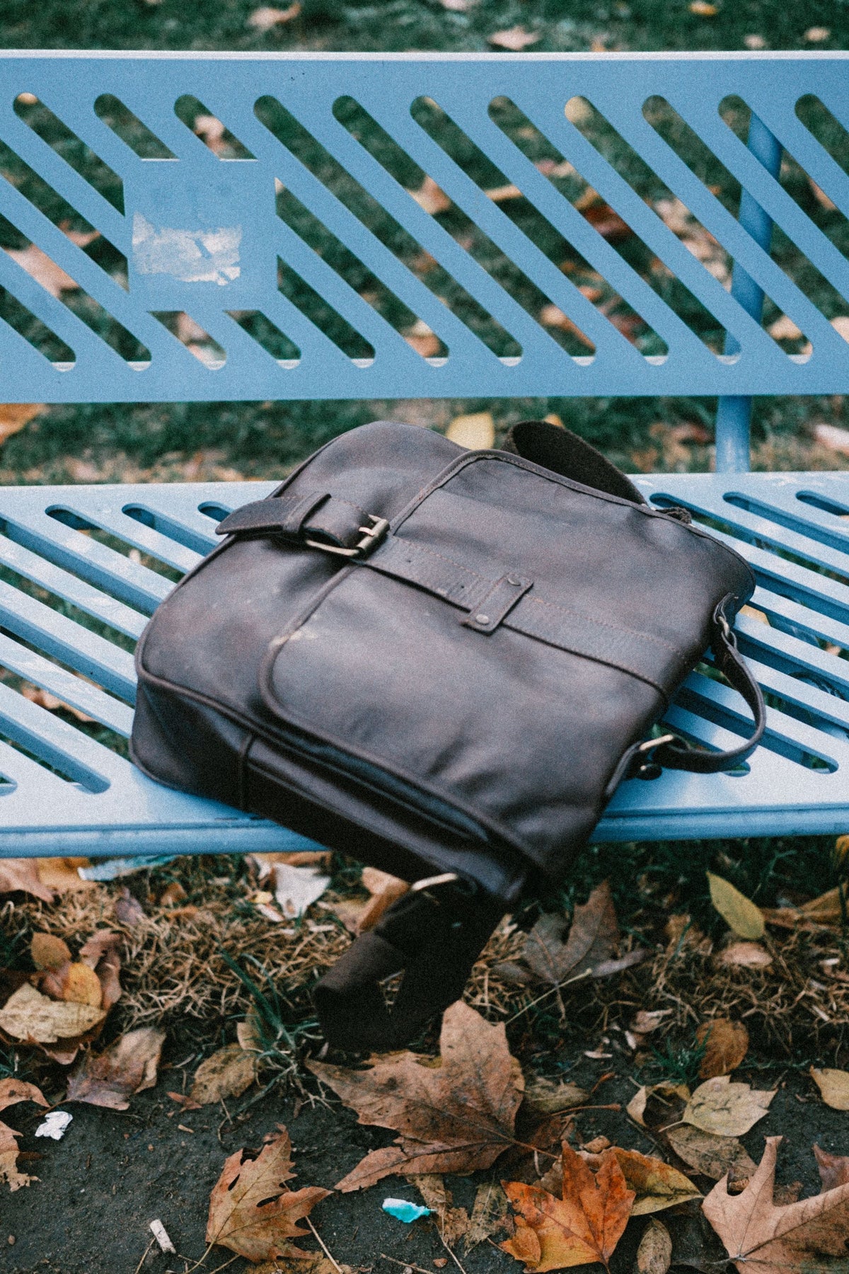 Worn leather messenger bag on a park bench in autumn