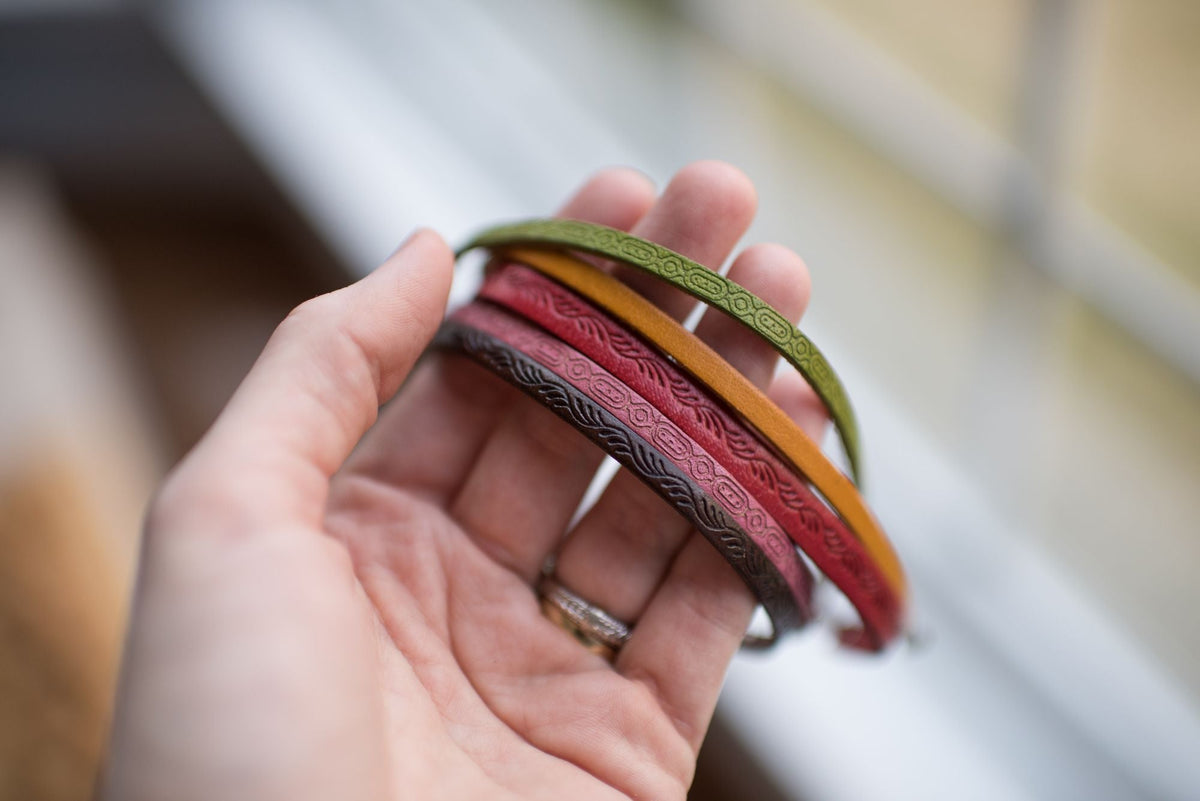 Hand holding a stack of colorful leather bracelets