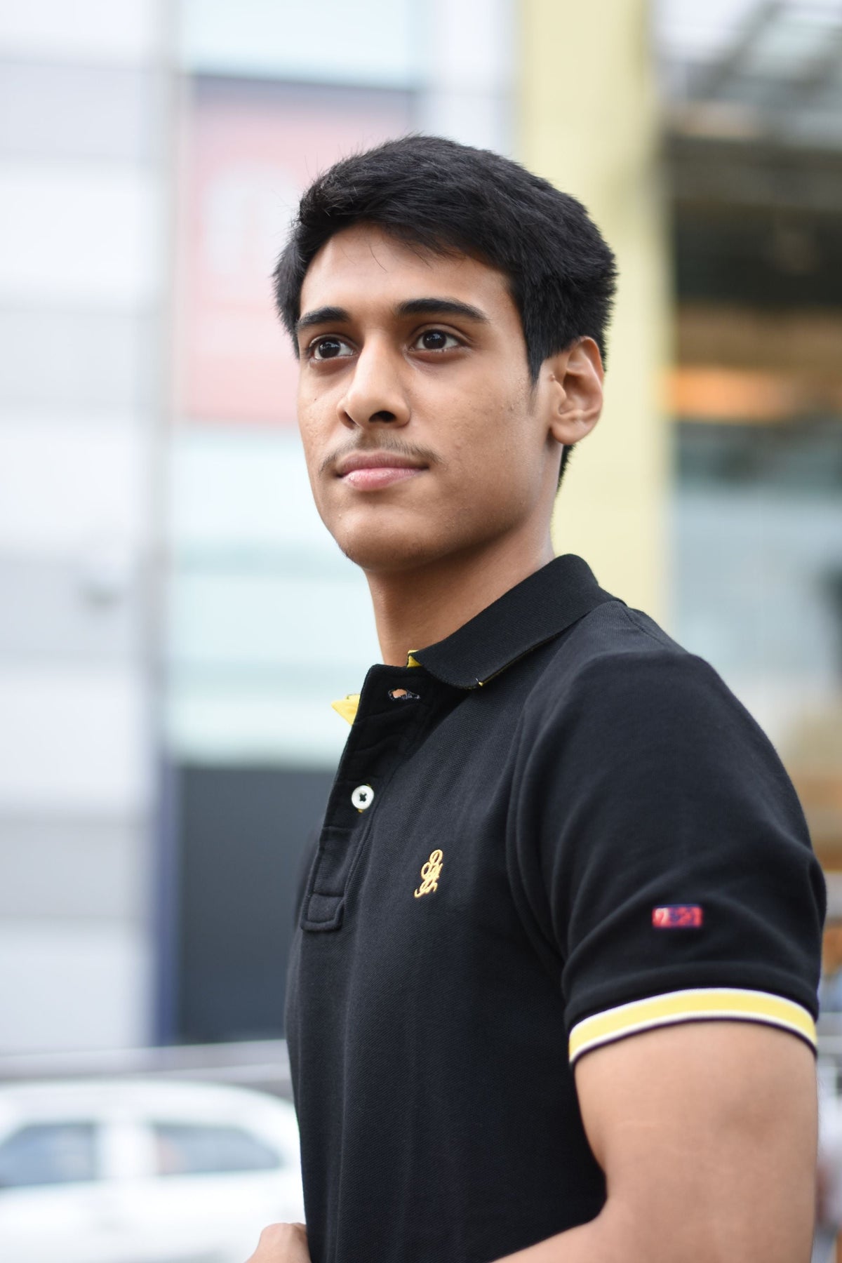 Young man wearing a black polo shirt outdoors