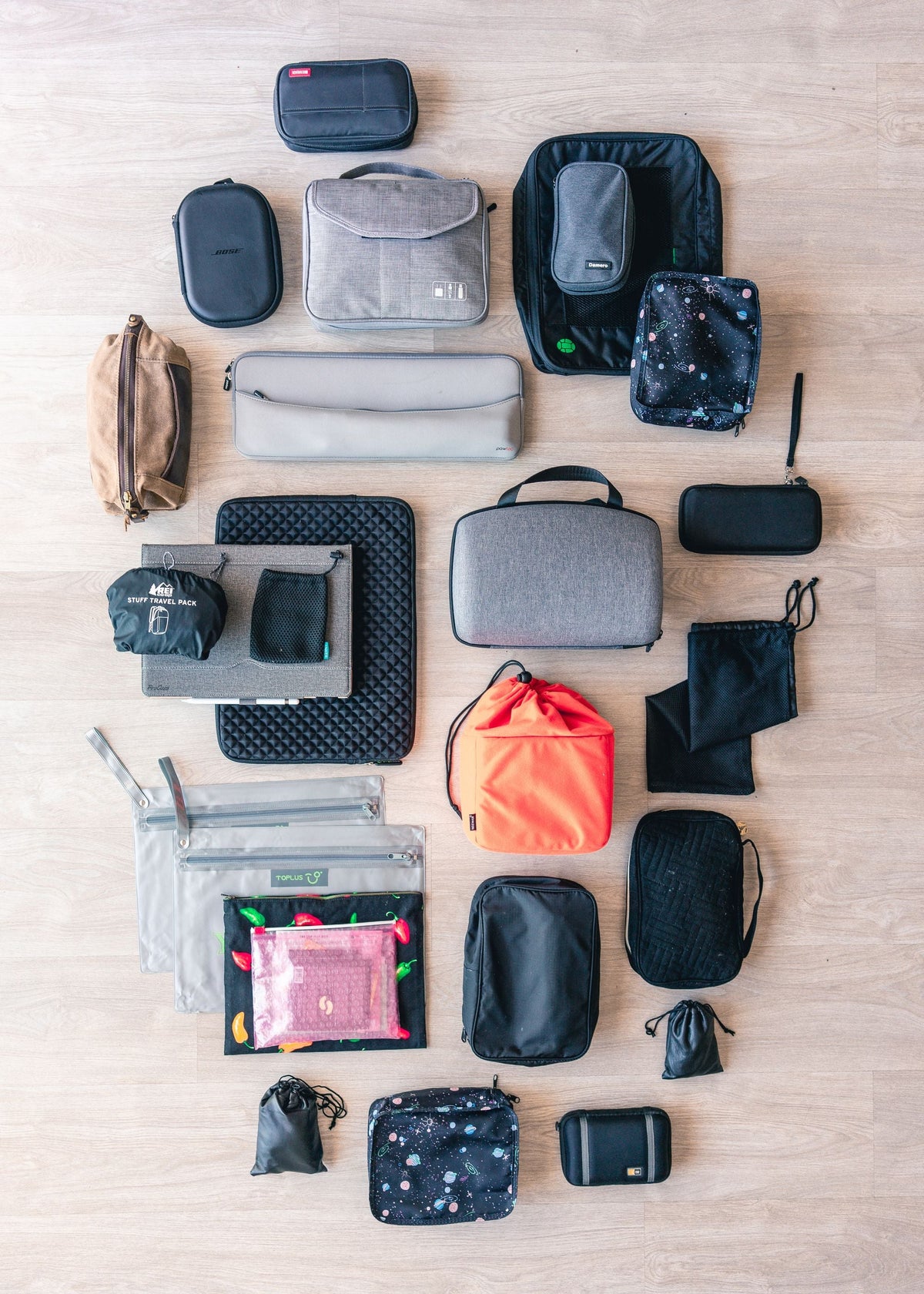 Flat lay of assorted travel pouches and organizer bags on a wood floor