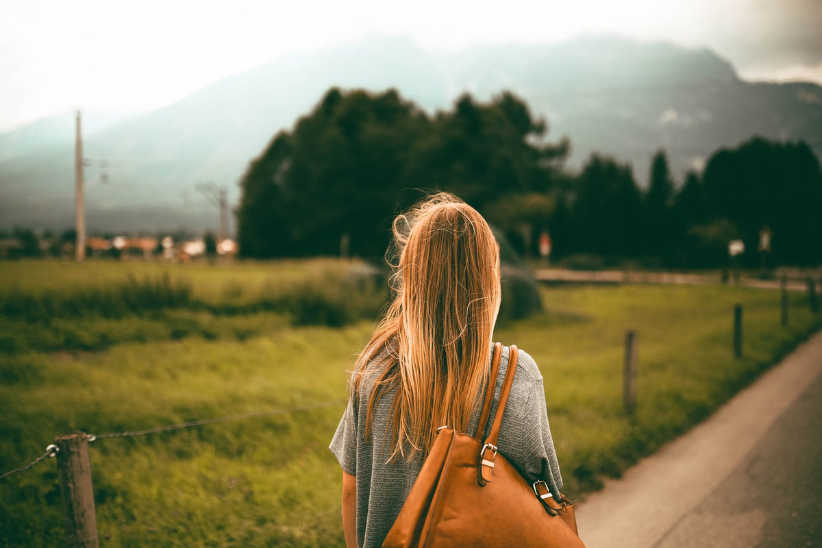 Woman carrying a brown leather shoulder bag outdoors