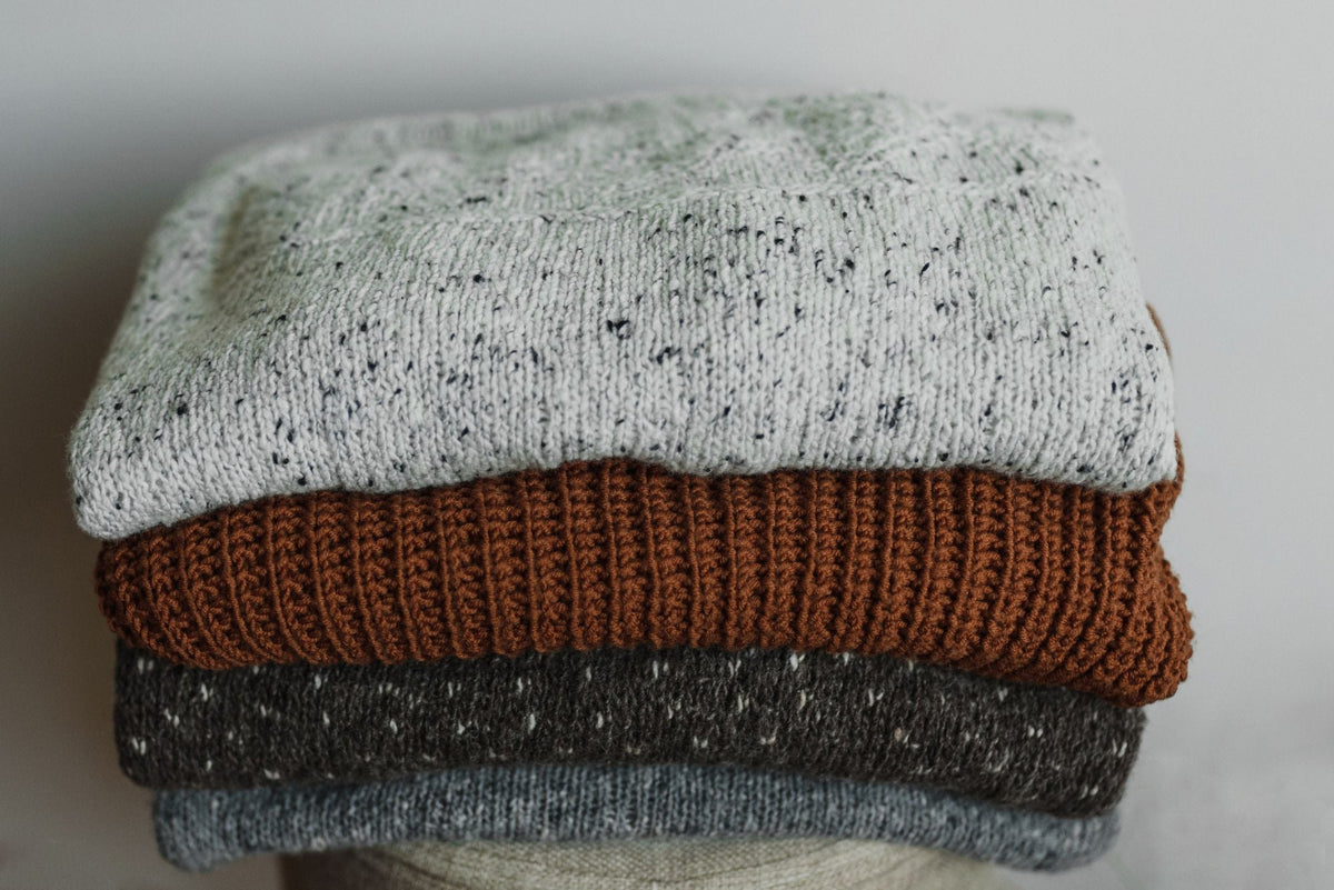 Stack of cozy folded knitwear in autumn tones