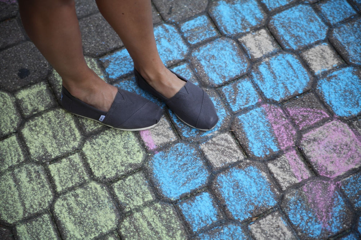 Woman wearing gray flat shoes on colorful chalk pavement