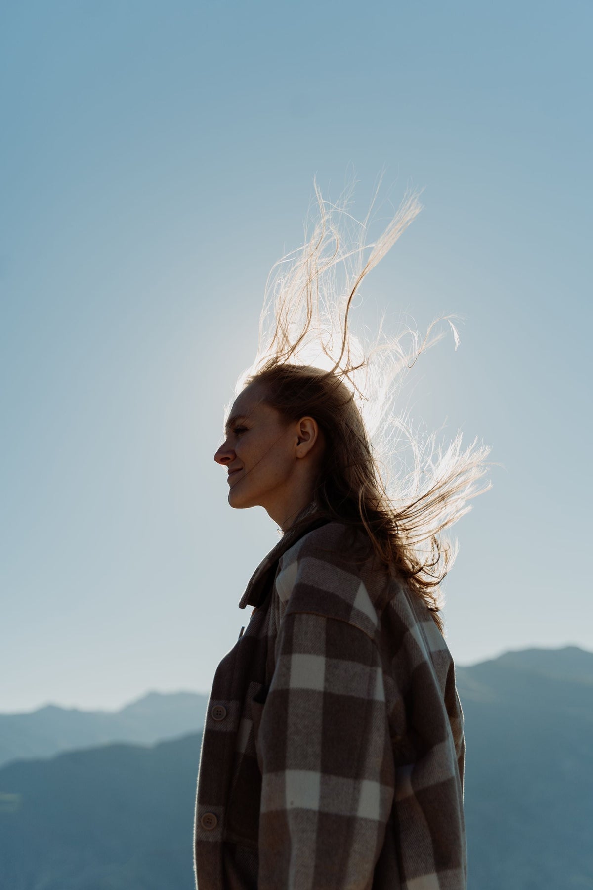 Woman wearing a plaid shacket with hair blowing in the wind