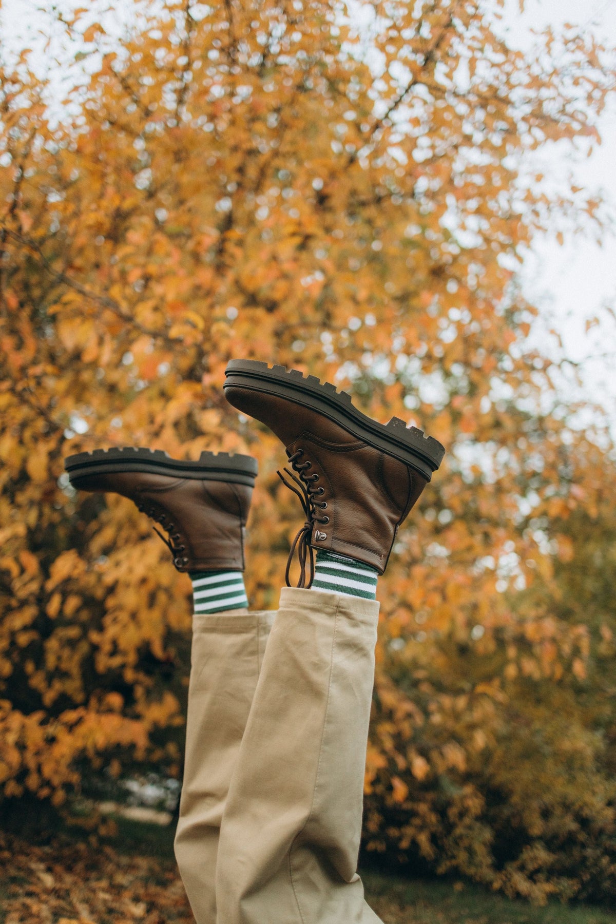 Playful shot of brown boots and khaki pants against autumn leaves