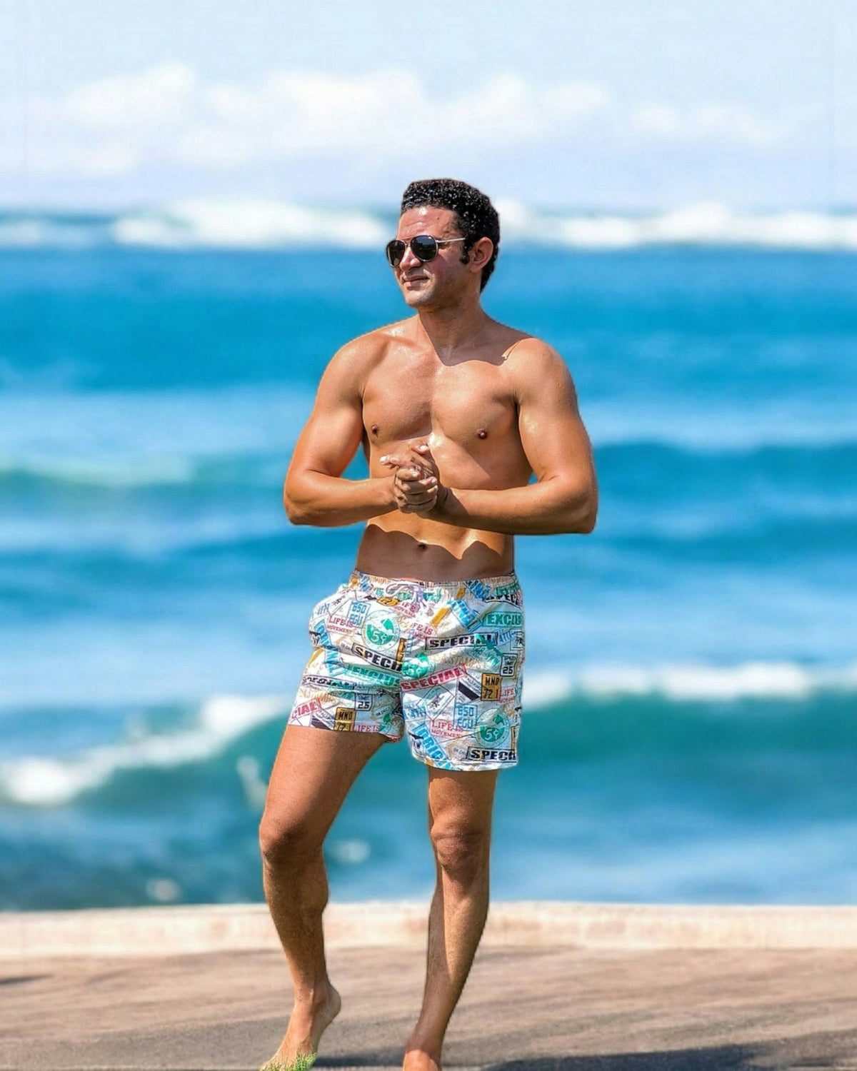 Man wearing patterned quick-dry swim trunks on a beach boardwalk