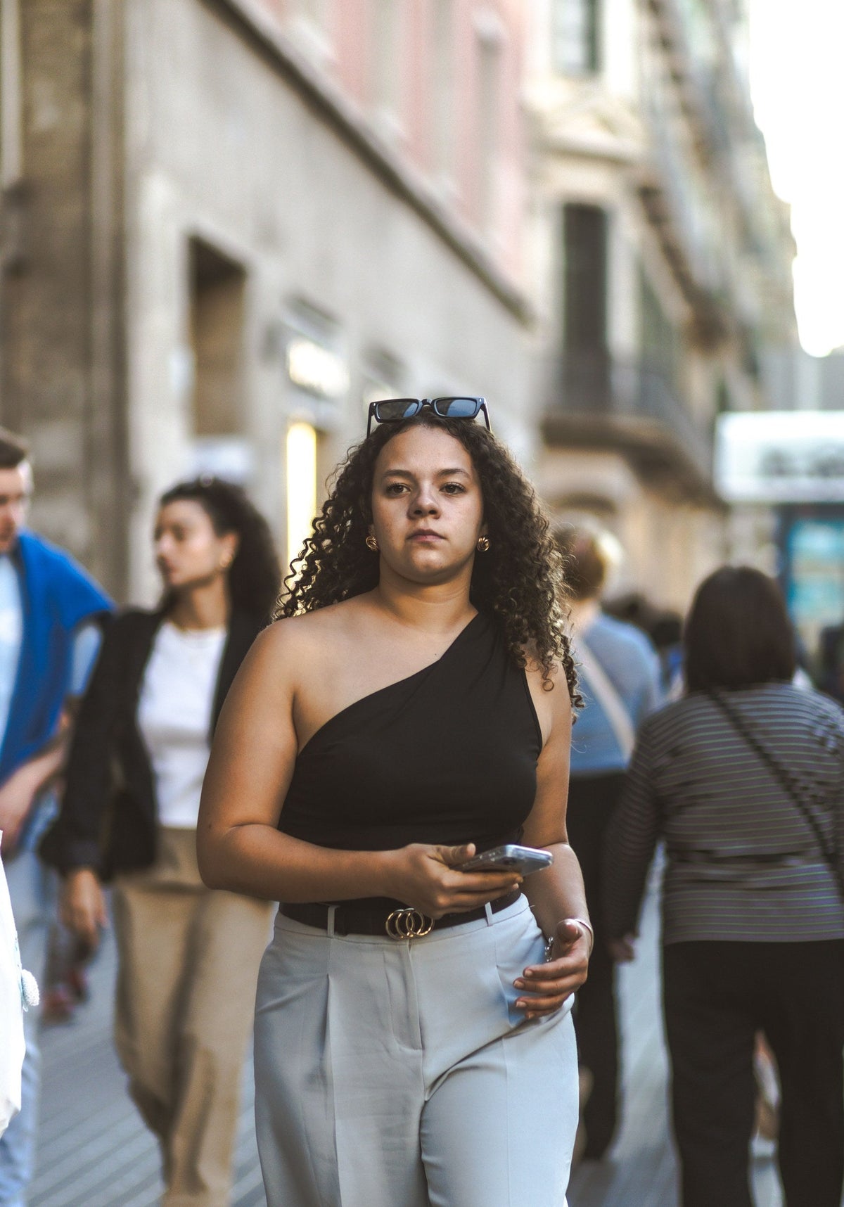 Plus-size woman in a stylish top and trousers walking on a city street while traveling