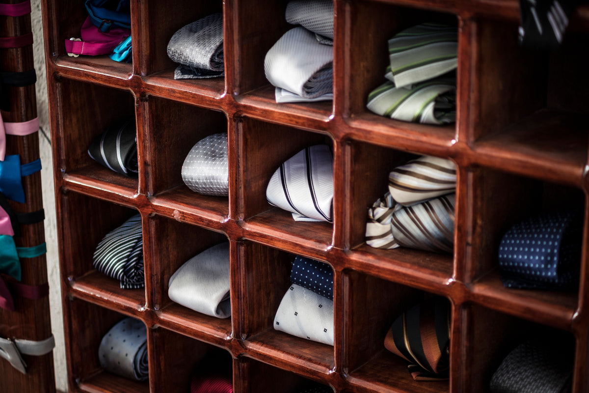 Silk neckties neatly rolled and arranged in a wooden closet organizer