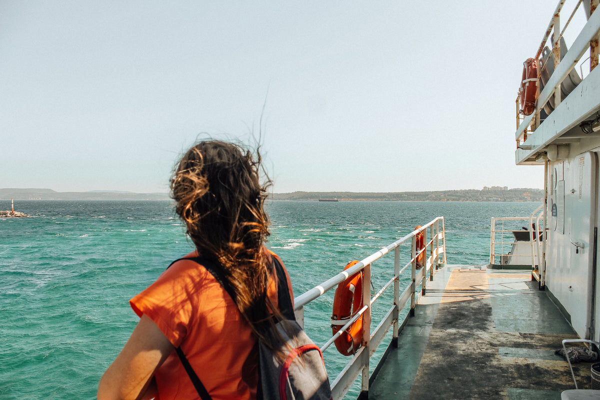 Solo traveler looking out at the ocean from a ship deck railing