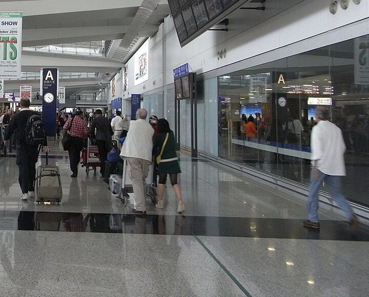 Travelers pulling luggage through a busy airport terminal