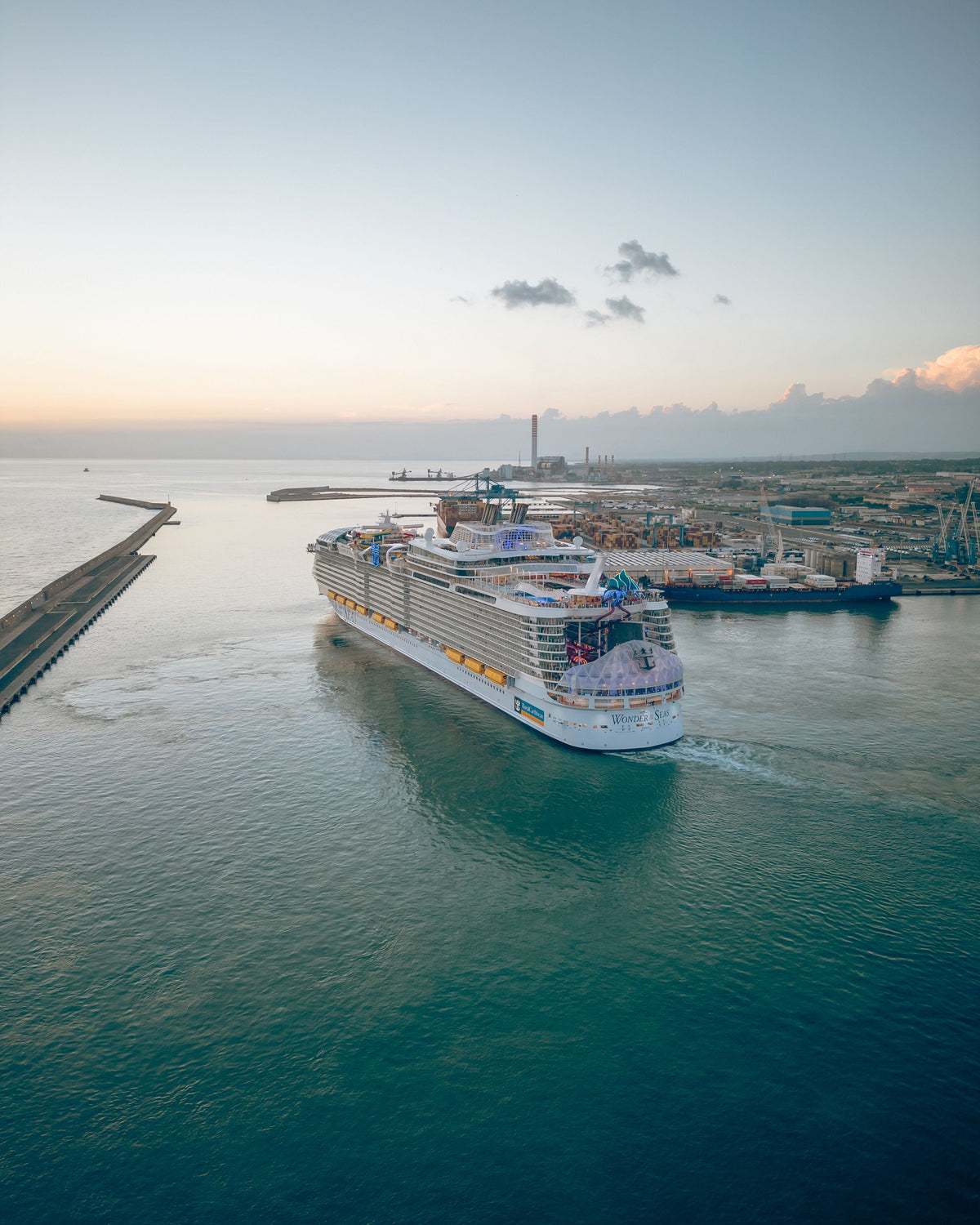 Aerial view of a cruise ship departing a busy port at dawn