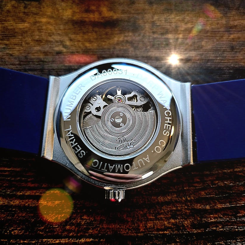 Watch with blue strap and visible mechanism on a wooden surface