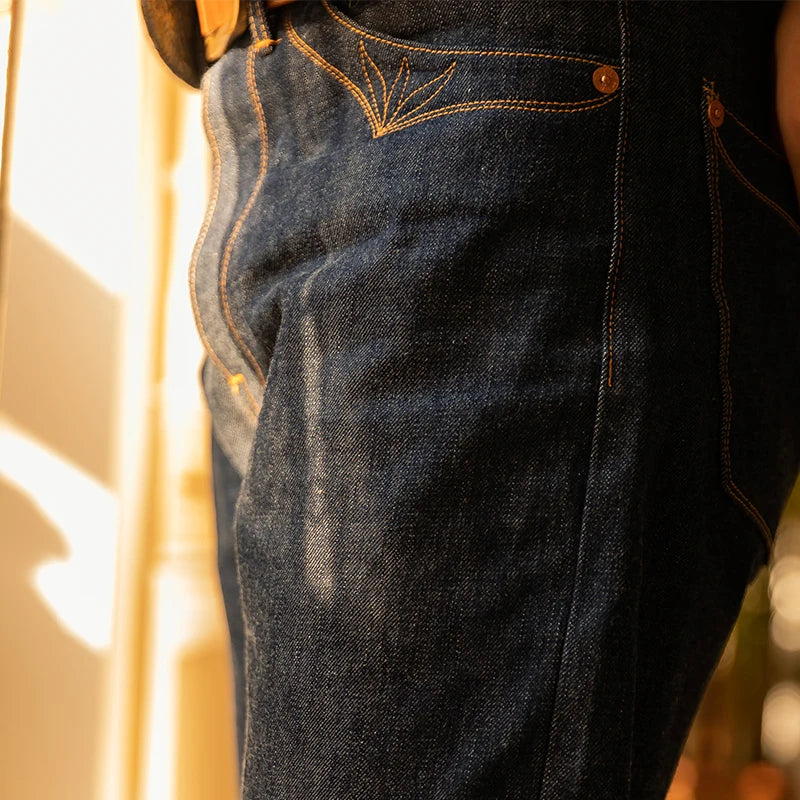 Close-up of a person wearing dark blue jeans with a blurred background