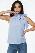 Woman wearing a blue and white striped halter top with a bow detail on a white background