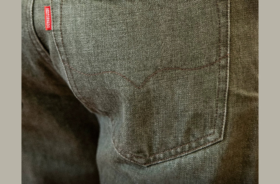 Close-up of a green denim pocket with a brand label, featuring text in Chinese and English.